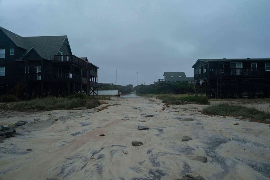 A road covered in sand is seen in the midst of a storm, Sunday, Oct. 12, 2025, in Buxton, N.C. (AP Photo/Allison Joyce)