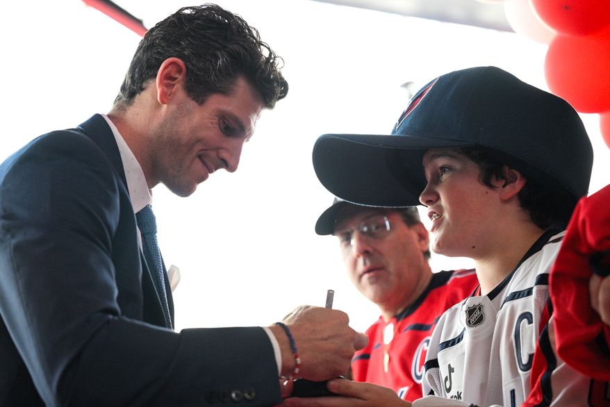 Washington Capitals forward Nic Dowd (26) signs an autograph for a junior Caps fan prior to facing the Boston Bruins in the season opener at Capital One Arena, Washington, D.C., October 8, 2025. (Photo by Brian Murphy for the Washington Times)