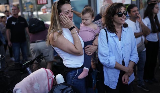 People react as they gather to watch a live broadcast of Israeli hostages released from Gaza at a plaza known as hostages square in Tel Aviv, Israel, Monday, Oct. 13, 2025. The release took place as part of a cease-fire agreement between Israel and Hamas. (AP Photo/Oded Balilty)