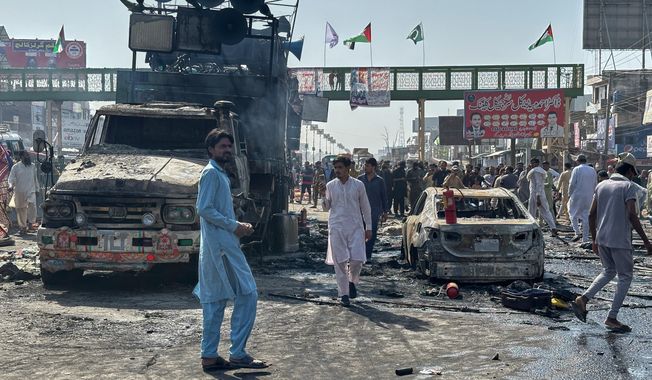 Local residents stand by burnt vehicles after police in Pakistan clashed with thousands of protesters during a march in support of Palestinians, in Muridke near Lahore, Pakistan, Monday, Oct. 13, 2025. (AP Photo/Jahanzeb Khan)