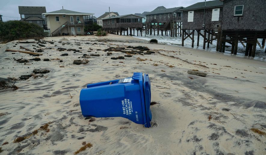 A recycling bin sits on a beach after a storm, Monday, Oct. 13, 2025, in Buxton, N.C. (AP Photo/Allison Joyce)