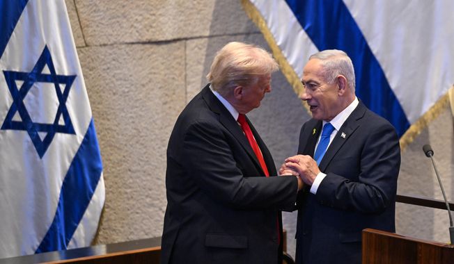 President Donald Trump clasps hands with Israeli Prime Minister Benjamin Netanyahu in the Knesset, Monday, Oct. 13, 2025, in Jerusalem. (Kenny Holston/The New York Times via AP, Pool)