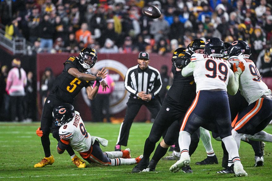 Washington Commanders quarterback Jayden Daniels (5) is hit low by Chicago Bears defensive back Jaquan Brisker (9) on a fourth quarter pass attempt at Northwest Stadium in Landover, Maryland, October 13, 2025. (Photo by Brian Murphy for the Washington Times)