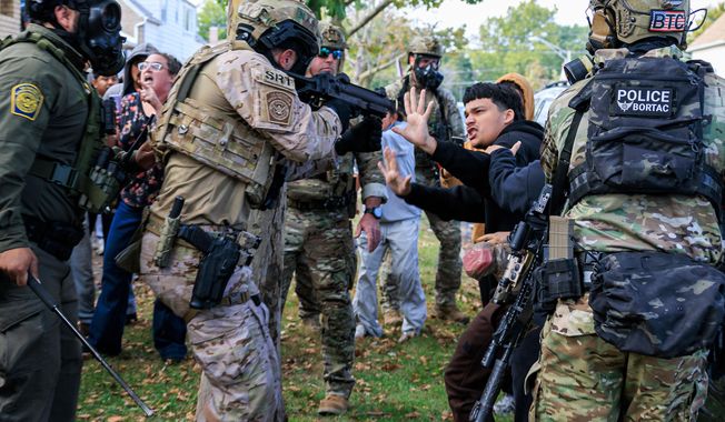A law enforcement officer points a crowd control weapon at a protester in East Side, Chicago, Tuesday, Oct. 14, 2025. (Anthony Vazquez/Chicago Sun-Times via AP)