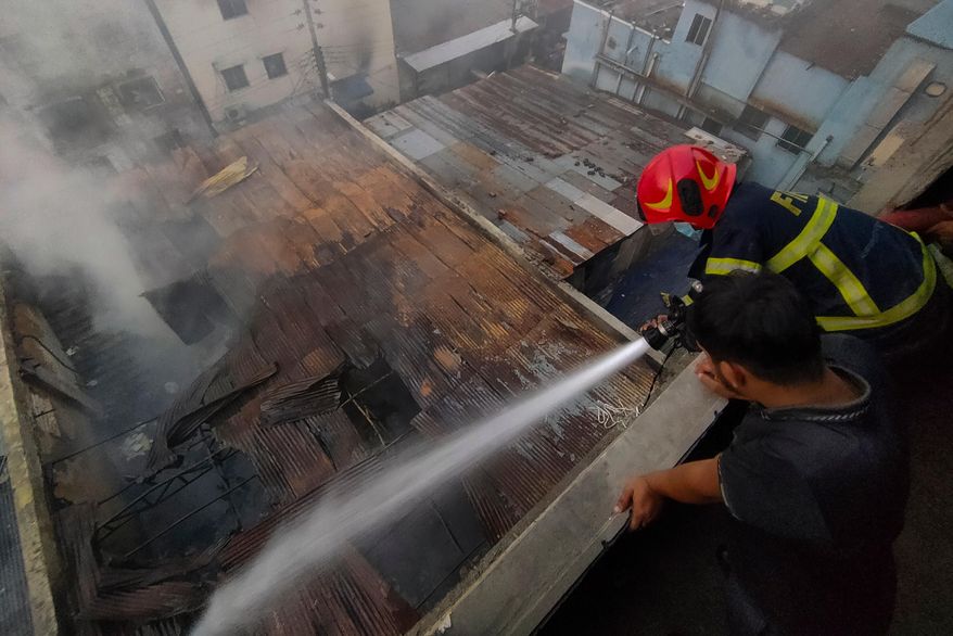 A firefighter sprays water to douse the flames after a fire broke out at a chemical warehouse and garment factory in Mirpur, Dhaka, Bangladesh, Tuesday, Oct. 14, 2025. (AP Photo/Mahmud Hossain Opu)