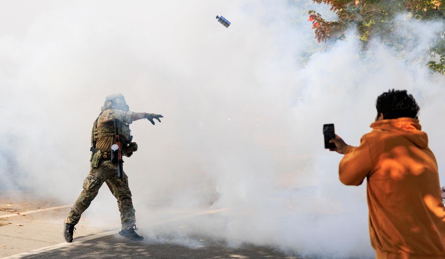 A government official throws a tear gas canister towards protesters in Chicago, Tuesday, Oct. 14, 2025. (Anthony Vazquez/Chicago Sun-Times via AP)
