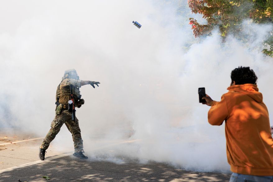 A government official throws a tear gas canister towards protesters in Chicago, Tuesday, Oct. 14, 2025. (Anthony Vazquez/Chicago Sun-Times via AP)