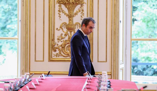 France's reappointed Prime Minister Sebastien Lecornu walks past a meeting table as he welcomes the newly appointed members of his cabinet in Paris, Monday, Oct. 13, 2025. (Alain Jocard, Pool photo via AP)