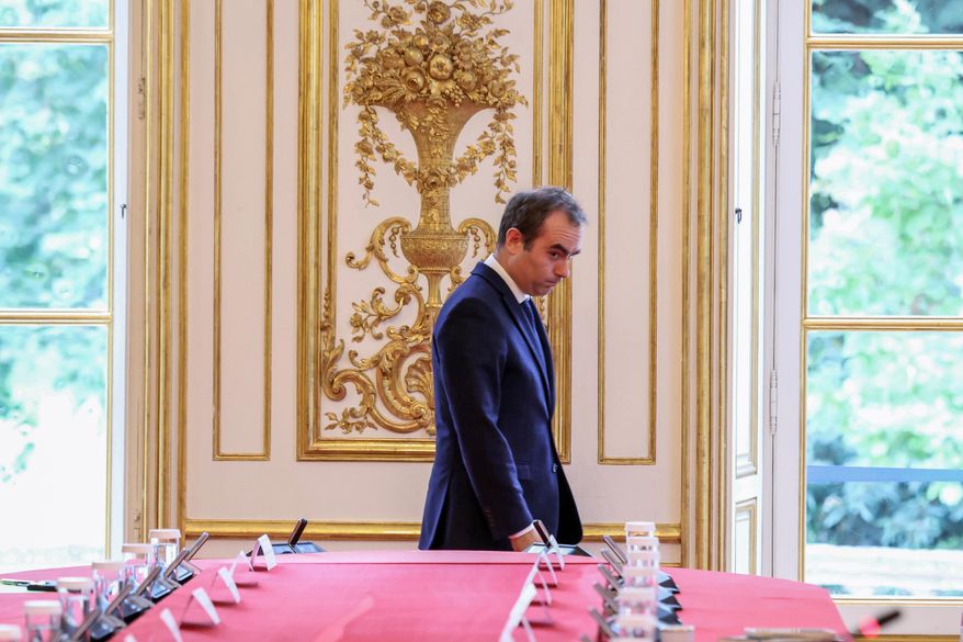 France's reappointed Prime Minister Sebastien Lecornu walks past a meeting table as he welcomes the newly appointed members of his cabinet in Paris, Monday, Oct. 13, 2025. (Alain Jocard, Pool photo via AP)