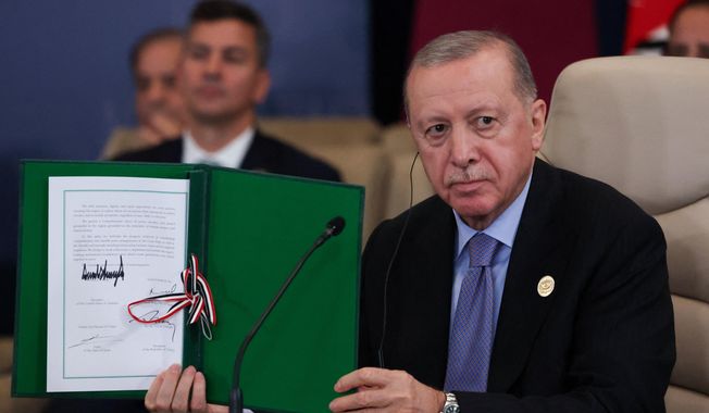 Turkey's President Recep Tayyip Erdogan holds a signed document during a summit to support ending the more than two-year Israel-Hamas war in Gaza after a breakthrough ceasefire deal, Monday, Oct. 13, 2025, in Sharm El Sheikh, Egypt. (Suzanne Plunkett/Pool via AP)