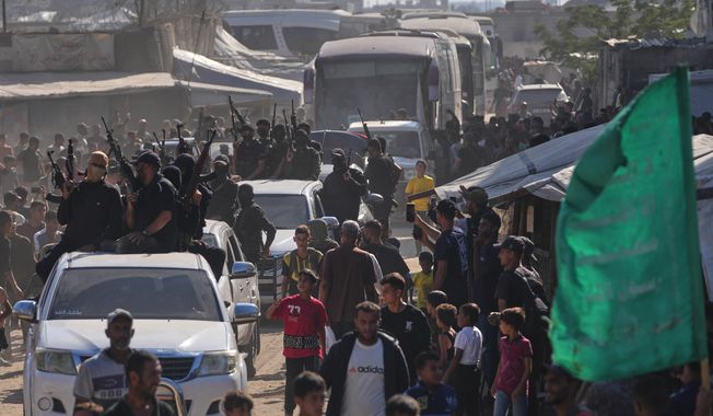 Hamas gunmen escort buses carrying freed Palestinian prisoners arriving in the Gaza Strip after their release from Israeli jails under a ceasefire agreement between Hamas and Israel, in Khan Younis, southern Gaza Strip, Monday, Oct. 13, 2025. (AP Photo/Jehad Alshrafi)