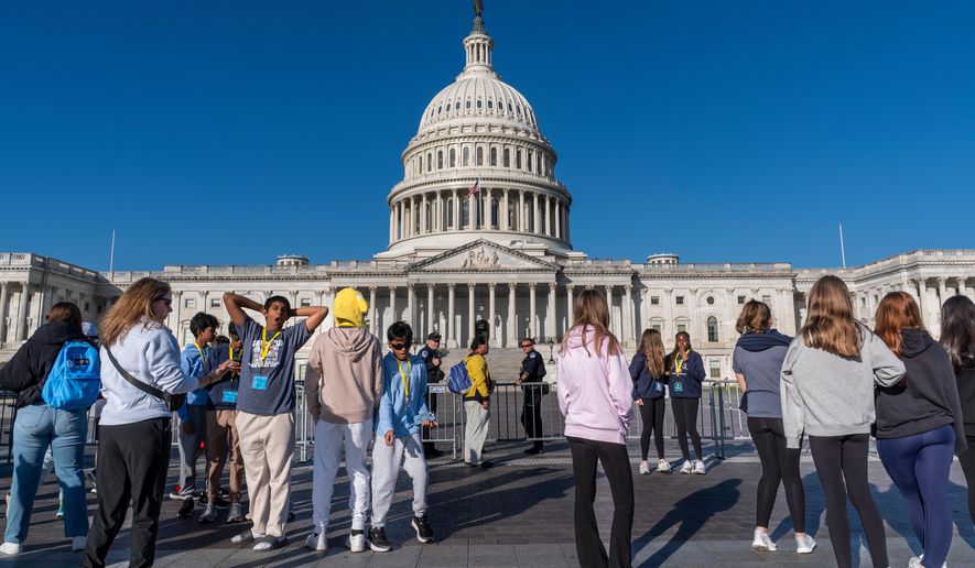 Students from Columbus, Ohio, wait outside a barrier as U.S. Capitol Police watch over the East Plaza where congressional leaders will have a news conferences on the government shutdown at the Capitol in Washington, Wednesday, Oct. 15, 2025. (AP Photo/J. Scott Applewhite)