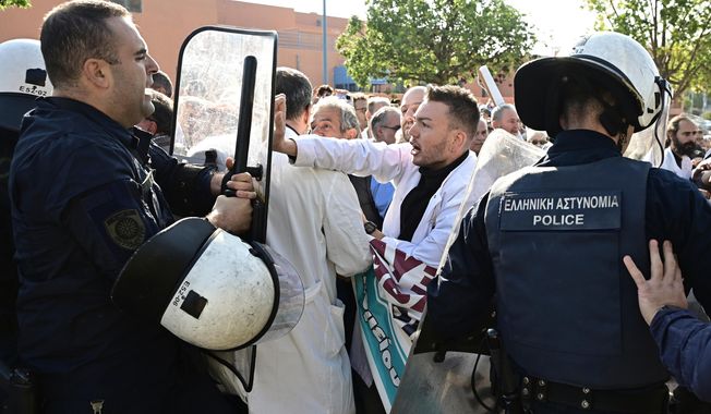 Medical workers scuffle with riot police after the staff gathered to protest the state of public health services during a visit to the hospital by the country's prime minister in Athens, Greece, Wednesday, Oct. 15, 2025. (Michalis Karayiannis/Eurokinissi via AP)