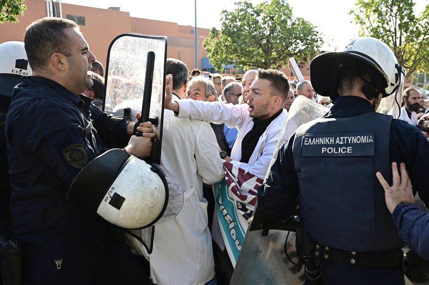 Medical workers scuffle with riot police after the staff gathered to protest the state of public health services during a visit to the hospital by the country's prime minister in Athens, Greece, Wednesday, Oct. 15, 2025. (Michalis Karayiannis/Eurokinissi via AP)