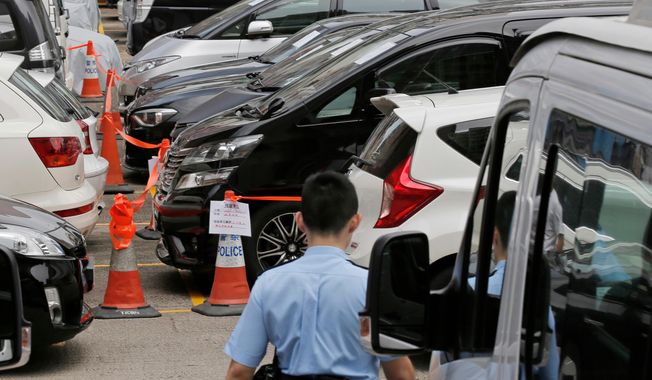 FILE - Impounded vehicles meant for Uber service, center, are parked behind a police cordon line at a police station in Hong Kong, on May 23, 2017. (AP Photo/Kin Cheung, File)