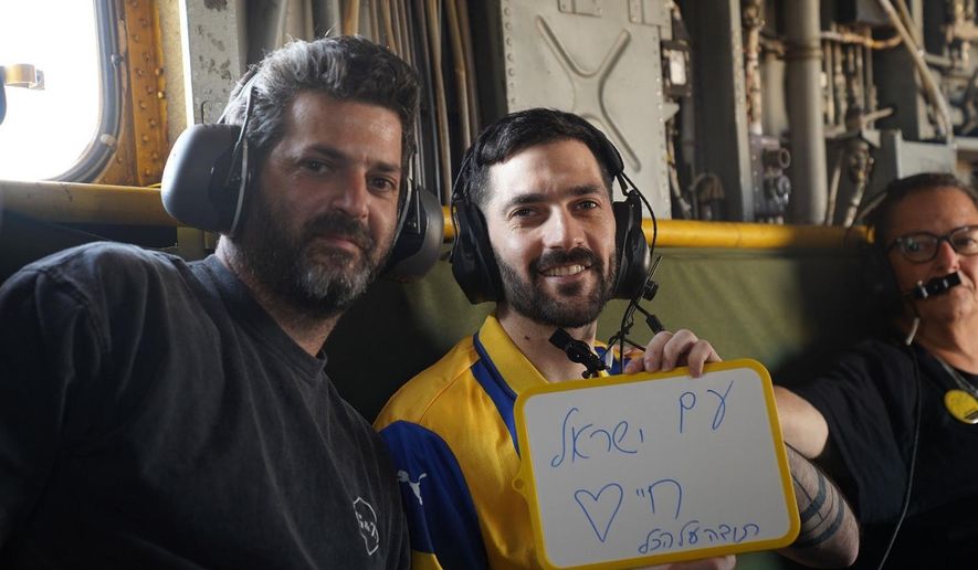 Gali Berman, carries a placard reading in Hebrew "The People of Israel Live," as he sits onboard an IAF helicopter en route to the hospital after being released from Hamas captivity, on Monday, Oct. 13, 2025. (IDF via AP)