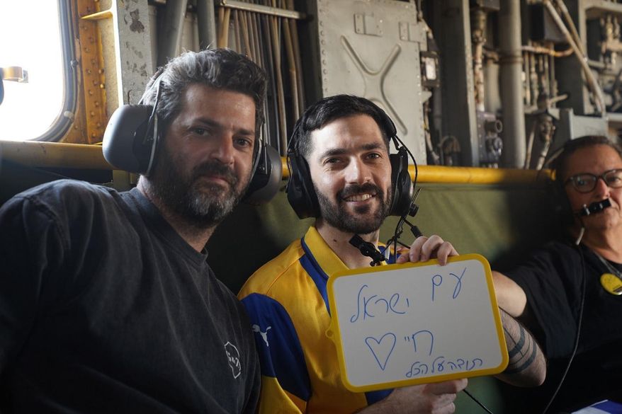 Gali Berman, carries a placard reading in Hebrew "The People of Israel Live," as he sits onboard an IAF helicopter en route to the hospital after being released from Hamas captivity, on Monday, Oct. 13, 2025. (IDF via AP)