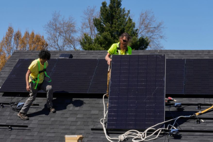 Brayan Santos, left, and Theodore Tanczuk, right, of solar installer YellowLite, put solar panels on the roof of a home in Lakewood, Ohio, April 16, 2025. (AP Photo/Sue Ogrocki, File)