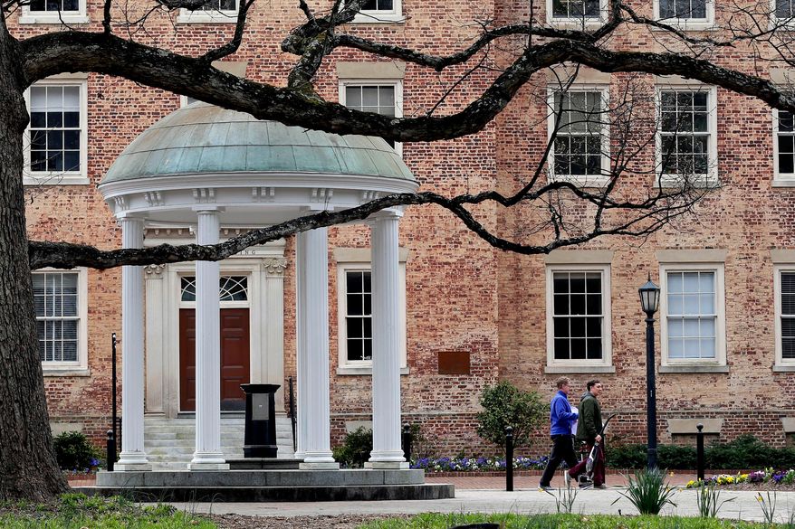 FILE - People walk through University of North Carolina campus March 18, 2020, in Chapel Hill, N.C. (AP Photo/Gerry Broome, File)