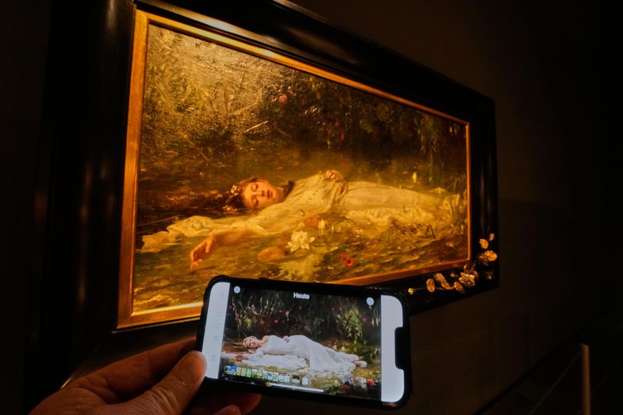 The opening part of Taylor Swift's video "The Fate of Ophelia" is displayed on a mobile phone in a museum showing a painting by Art Nouveau painter Friedrich Heyser showing Ophelia, a Shakespeare Character, in Wiesbaden, Germany, Thursday, Oct. 16, 2025. (AP Photo/Michael Probst)