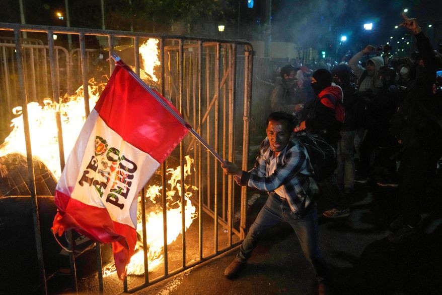 FILE - A demonstrator waves a Peruvian flag as a cardboard doll burns in front of Congress during a protest against new President Jose Jeri in Lima, Peru, Wednesday, Oct. 15, 2025. (AP Photo/Martin Mejia, File)