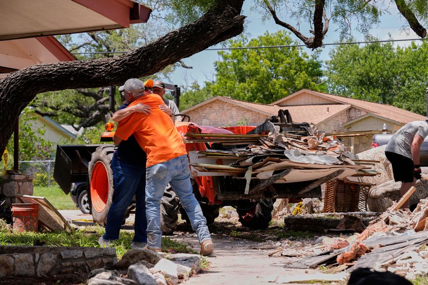 FILE - Homeowner Daniel Olivas hugs Lorrie McMillan, a chaplain with Texans on Mission Disaster Relief, as he clears debris from his home, which was heavily damaged from flash floods along the Guadalupe River in Kerrville, Texas, July 10, 2025. (AP Photo/Gerald Herbert, File)