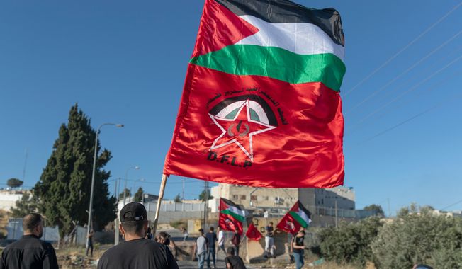 FILE - Palestinian protesters fly Palestinian flags and flags of the Democratic Front for the Liberation of Palestine, DFLP, during clashes with Israeli soldiers at the entrance the Jewish settlement of Beit El, background near the West Bank city of Ramallah, Tuesday, June. 15, 2021. (AP Photo/Nasser Nasser, file)