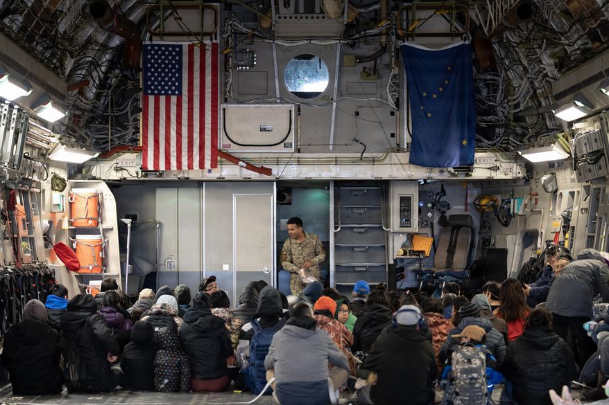 In this photo provided by the Alaska National Guard, Alaska Air National Guard Staff Sgt. Angel Reyes distributes hearing protection to passengers while evacuating Alaskans displaced in the aftermath of Typhoon Halong out of Bethel, Alaska, Wednesday, Oct. 15, 2025. (Alaska National Guard via AP)