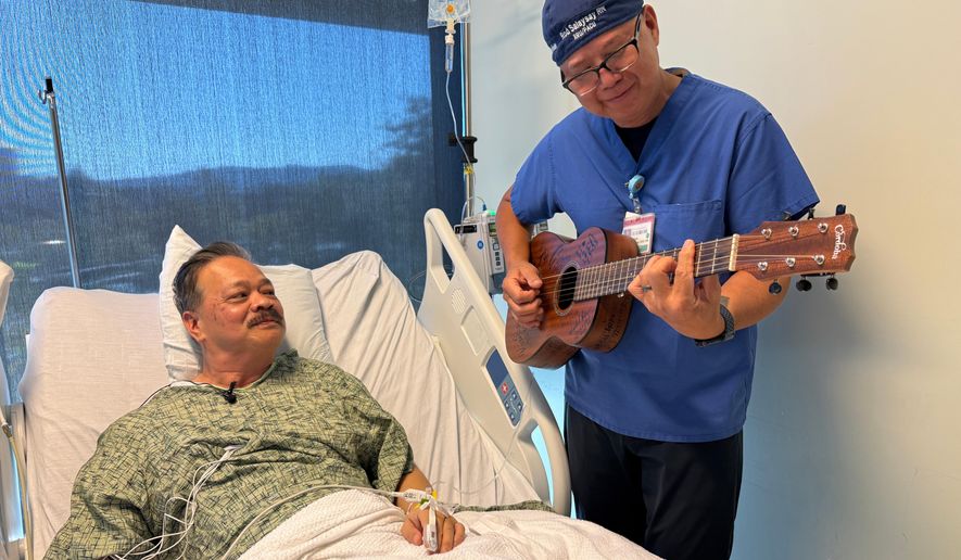 Nurse Rod Salaysay plays guitar for patient Richard Hoang in the recovery unit of UC San Diego Health in San Diego, Calif., on Sept. 30, 2025. (AP Photo/Javier Arciga)