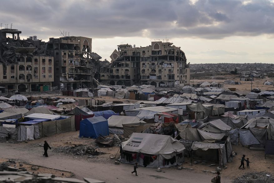 A tent camp for displaced Palestinians sits adjacent to destroyed homes and buildings in Khan Younis, Gaza Strip, Saturday, Oct. 18, 2025. (AP Photo/Jehad Alshrafi)