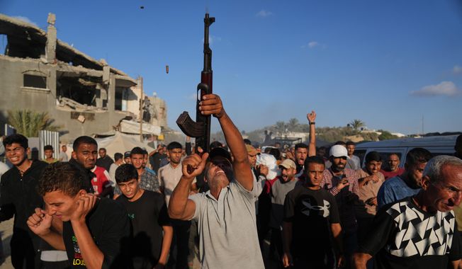 An armed man shoots in the air during the funeral of Palestinians killed by Israeli fire, in Deir al-Balah, Gaza Strip, Sunday, Oct. 19, 2025. (AP Photo/Abdel Kareem Hana)