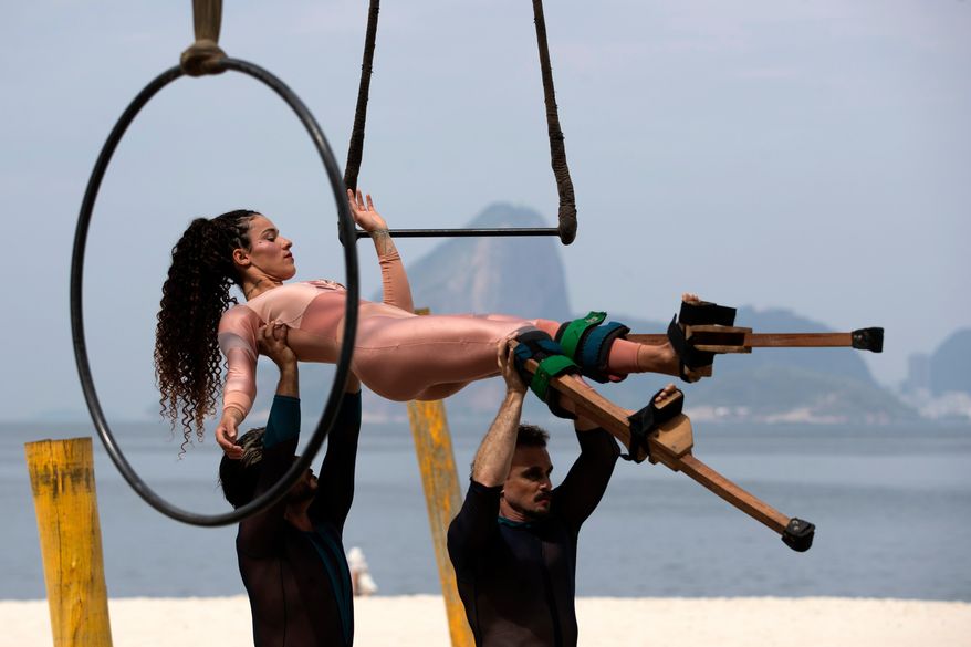 Artist Rosa Caitanya Hamilton Azevedo is carried by members of the group aerial circus "Pendurados” during a performance that explores healing from sexual violence through art and community, at Icarai Beach in Niteroi, Rio de Janeiro state, Brazil, Saturday, Oct. 18, 2025. (AP Photo/Bruna Prado)