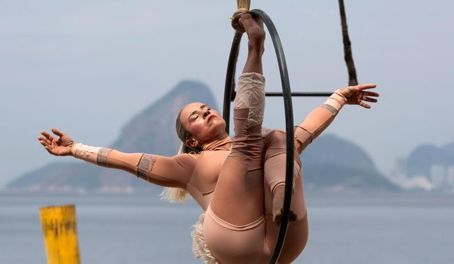 A member of the group aerial circus "Pendurados” performs in an open-air show that explores healing from sexual violence through art and community, at Icarai Beach in Niteroi, Rio de Janeiro state, Brazil, Saturday, Oct. 18, 2025. (AP Photo/Bruna Prado)