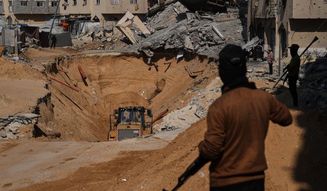 Members of the Hamas militant group search underground for the bodies of Israeli hostages amid destroyed buildings in Khan Younis, in the southern Gaza Strip, Sunday, Oct. 19, 2025. (AP Photo/Abdel Kareem Hana)