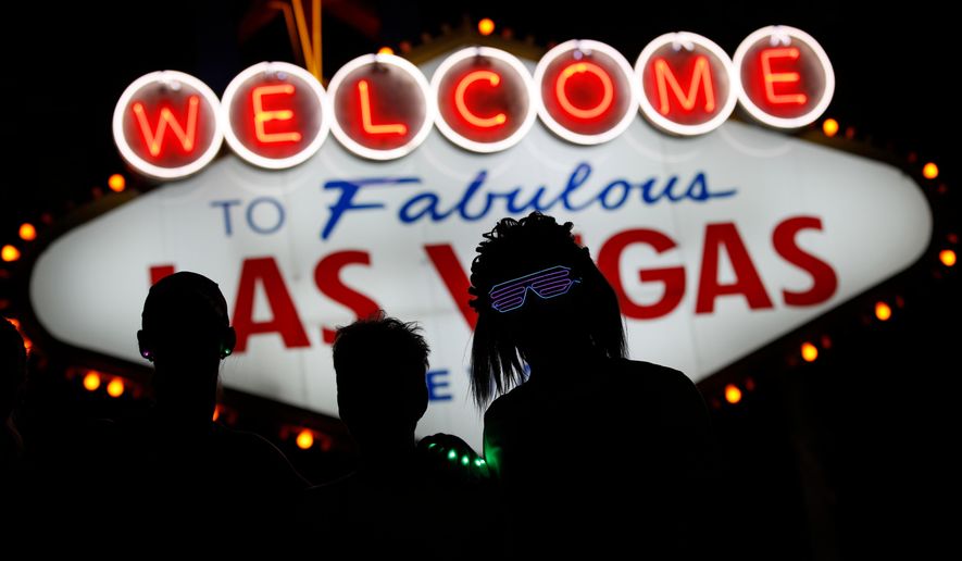 FILE - Runners stop to to have photos taken by official photographers at the Welcome to Las Vegas sign during the Rock 'n' Roll Las Vegas Marathon, Sunday, Nov. 12, 2017, in Las Vegas. (AP Photo/John Locher, File)