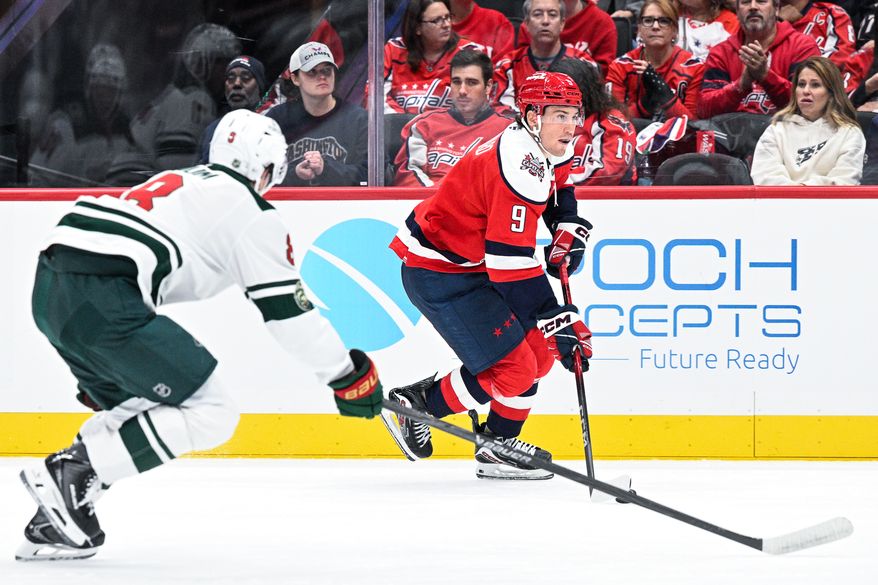 Washington Capitals forward Ryan Leonard (9) carries the puck up the boards with Minnesota Wild defenseman Zeev Buium (8) in pursuit at Capital One Arena, Washington, D.C., October 17, 2025. (Photo by Brian Murphy for the Washington Times)