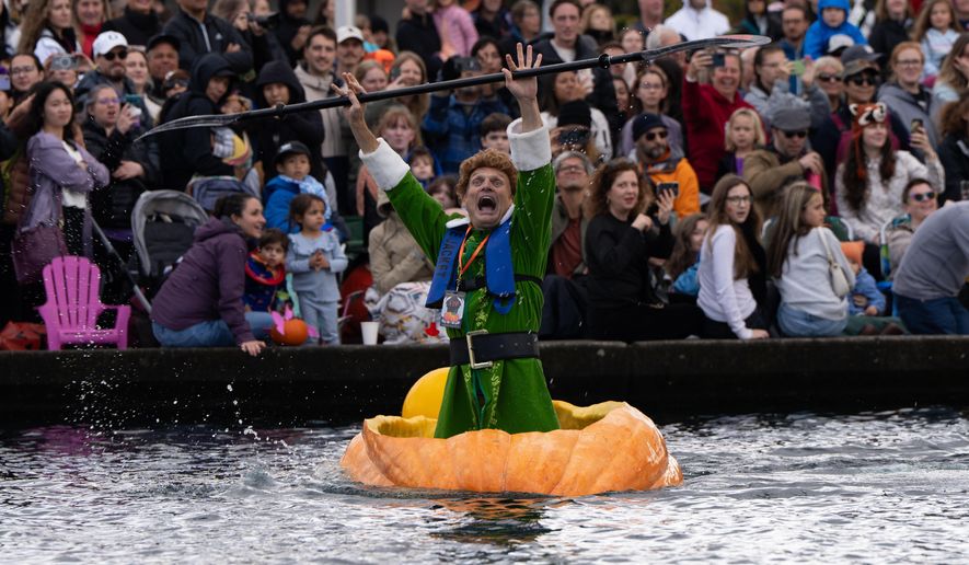 Gary Kristensen, dressed up as the character Buddy from the holiday movie "Elf," celebrates after winning a race during the West Coast Giant Pumpkin Regatta on Sunday, Oct. 19, 2025, in Tualatin, Ore. (AP Photo/Jenny Kane)