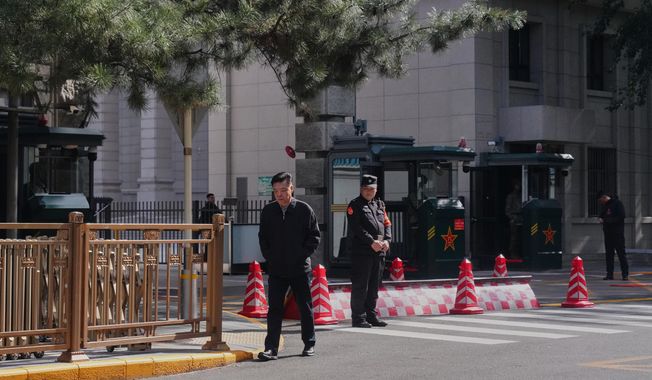 A man walks by Chinese security personnel guarding the entrance to the Jingxi Hotel where the Communist Party's Central Committee is holding its fourth plenum, in Beijing, Monday, Oct. 20, 2025. (AP Photo/Andy Wong)