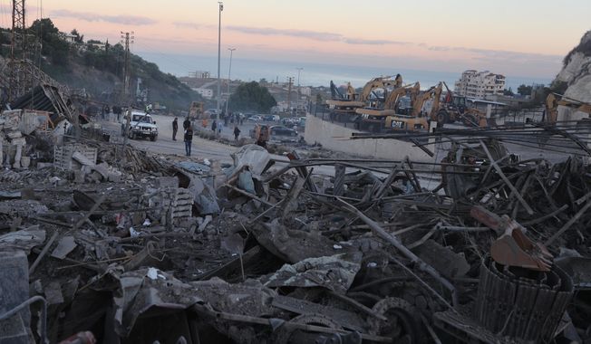 People gather at a site that sold heavy machinery, where a large number of vehicles were destroyed in Israeli airstrikes, in the southern village of Msayleh, Lebanon, Saturday, Oct. 11, 2025. (AP Photo/Mohammed Zaatari)