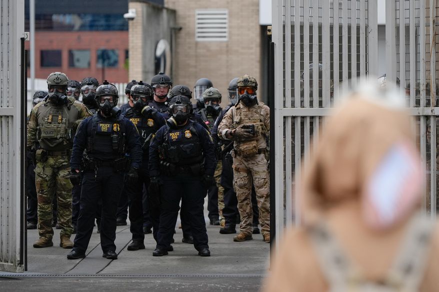 Law enforcement officers watch as the gates close at a U.S. Immigration and Customs Enforcement facility as people protest outside on Saturday, Oct. 11, 2025, in Portland, Ore. (AP Photo/Jenny Kane) **FILE**