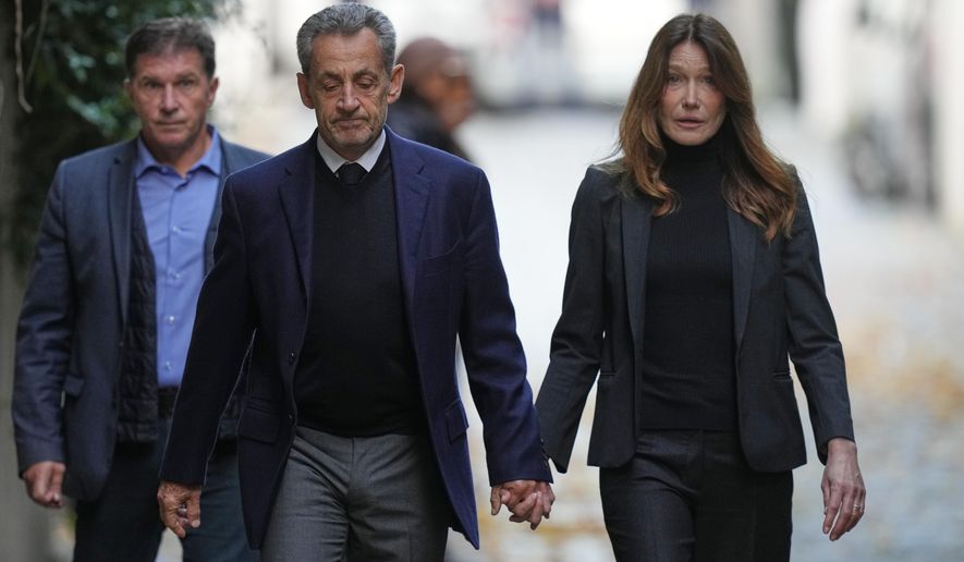Former French President Nicolas Sarkozy and his wife Carla Bruni-Sarkozy leave their home Tuesday, Oct. 21, 2025 in Paris as Nicolas Sarkozy heads to prison to serve time for a criminal conspiracy to finance his 2007 election campaign with funds from Libya. (AP Photo/Thibault Camus)