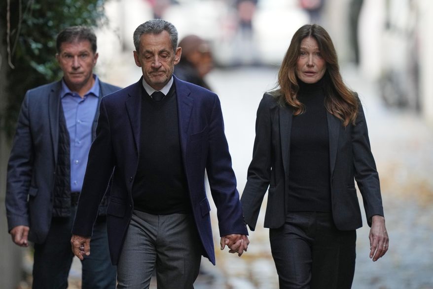 Former French President Nicolas Sarkozy and his wife Carla Bruni-Sarkozy leave their home Tuesday, Oct. 21, 2025 in Paris as Nicolas Sarkozy heads to prison to serve time for a criminal conspiracy to finance his 2007 election campaign with funds from Libya. (AP Photo/Thibault Camus)