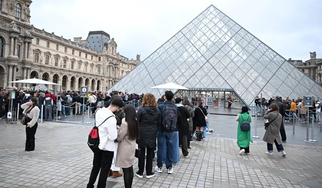 People queue outside the Louvre museum in Paris on Monday, Oct. 20, 2025, although it remains closed for the day after Sunday's jewels robbery. (AP Photo/Emma Da Silva)
