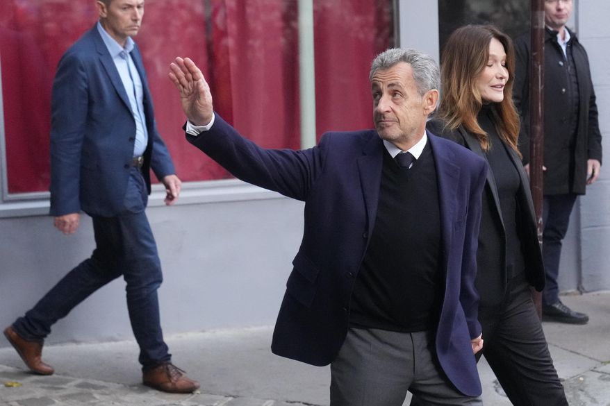 Former French President Nicolas Sarkozy and his wife Carla Bruni-Sarkozy leave their home Tuesday, Oct. 21, 2025 in Paris as Nicolas Sarkozy heads to prison to serve time for a criminal conspiracy to finance his 2007 election campaign with funds from Libya. (AP Photo/Thibault Camus)