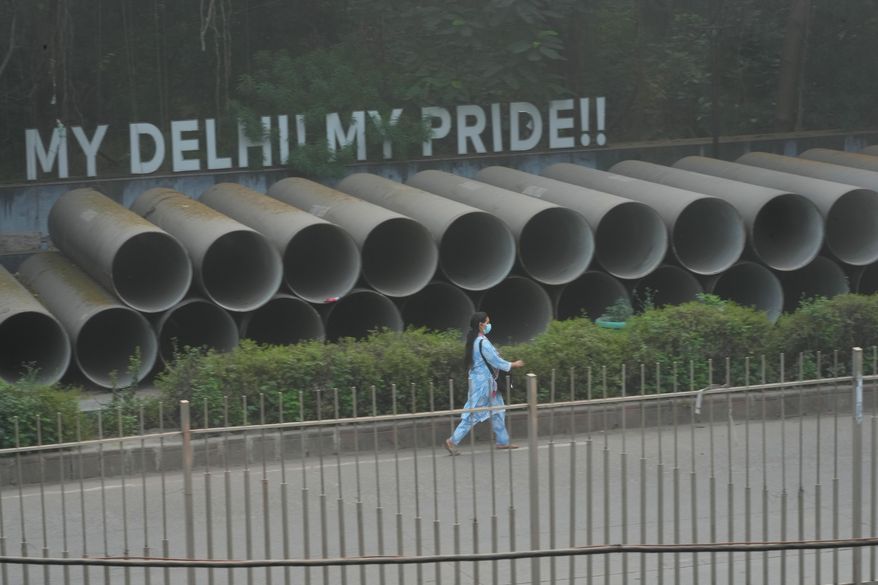 A woman wears a face mask as she walks amidst morning smog a day after Diwali festival in New Delhi, India, Tuesday, Oct. 21, 2025. (AP Photo/Manish Swarup)