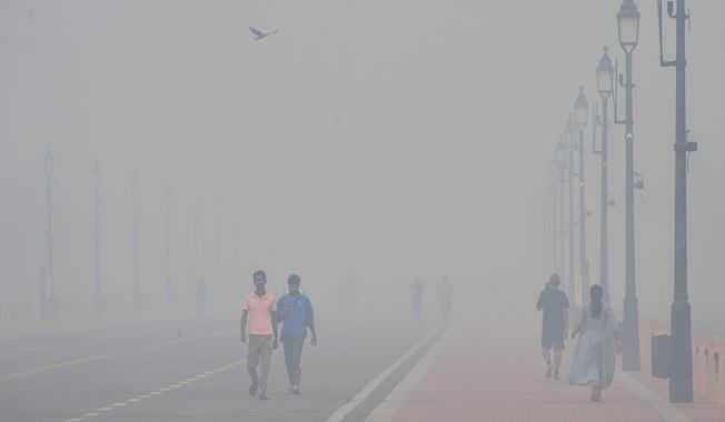 People walk in the morning near the India Gate monument amidst morning smog a day after Diwali festival in New Delhi, India, Tuesday, Oct. 21, 2025. (AP Photo/Manish Swarup)