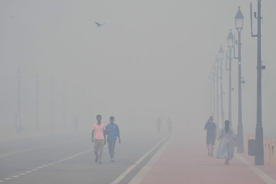 People walk in the morning near the India Gate monument amidst morning smog a day after Diwali festival in New Delhi, India, Tuesday, Oct. 21, 2025. (AP Photo/Manish Swarup)