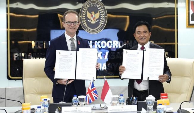 UK Ambassador to Indonesia Dominic Jermey, left, and Indonesia's Coordinating Minister for Legal, Human Rights, Immigration and Correctional Affairs Yusril Ihza Mahendra show the document practical arrangement on transfer of sentenced British prisoners in Jakarta, Indonesia, Tuesday, Oct. 21, 2025. (Kemenko Kumham Imipas via AP)