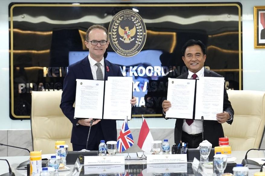 UK Ambassador to Indonesia Dominic Jermey, left, and Indonesia's Coordinating Minister for Legal, Human Rights, Immigration and Correctional Affairs Yusril Ihza Mahendra show the document practical arrangement on transfer of sentenced British prisoners in Jakarta, Indonesia, Tuesday, Oct. 21, 2025. (Kemenko Kumham Imipas via AP)