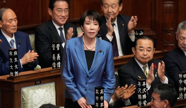 Lawmakers applaud as Sanae Takaichi, standing, was elected as Japan's new prime minister during the extraordinary session of the lower house, in Tokyo, Japan, Tuesday, Oct. 21, 2025.(AP Photo/Eugene Hoshiko)